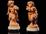 une paire de figurines sculptées représentant des chérubins, sur des socles en marbre