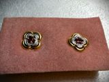a close up of a pair of earrings on a pink cloth