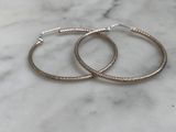 a pair of silver hoop earrings sitting on top of a marble counter