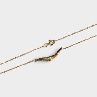 un collier plaqué or composé d'une longue chaîne sur laquelle est accroché un oiseau