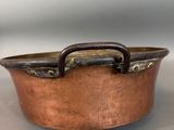 an old copper pan with a handle on a table