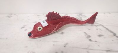 figurine de poisson rouge munie d'une étiquette, posée sur une surface en marbre