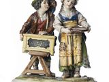 two figurines of two children with musical instruments on a white surface