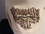 an image of a close up of a white dress with gold embroidery on it