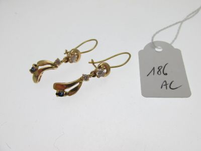 une paire de boucles d'oreilles en or avec une étiquette sur un fond blanc