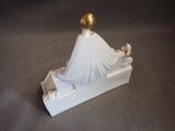 a white figurine with a gold ball on top of it