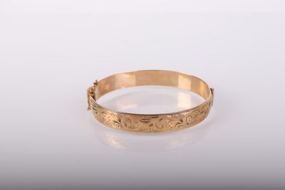 gros plan d'un bracelet en or sur une surface blanche