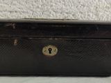 an old black suitcase sitting on a white surface