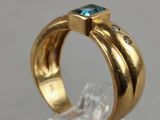 a close up of a gold ring with a blue topaz stone