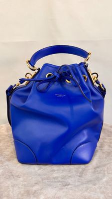 a blue bucket bag sitting on top of a white surface