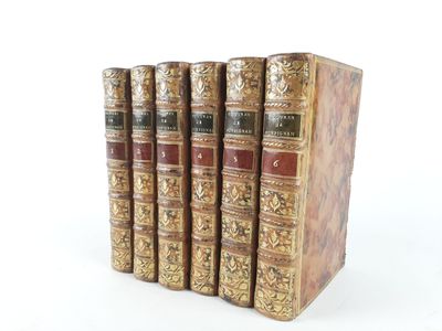 several old books are lined up in a row on a white surface