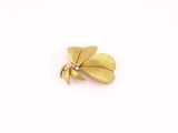 un gros plan d'une broche en feuille d'or sur fond blanc