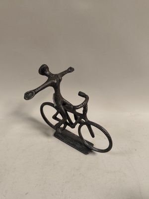 metal figurine of a man riding a bicycle on a sled