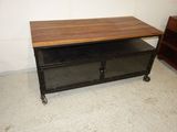 a table with a wooden top on wheels in a room