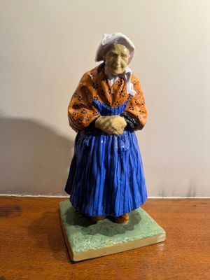 une figurine représentant une vieille femme assise sur une table