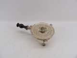 an antique silver plate with a black handle on a white surface