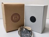 une photo montrant une montre posée à côté d'une boîte sur une table