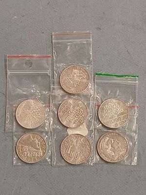 Plusieurs pièces se trouvent dans un sachet posé sur une table et fermé par une ficelle verte.