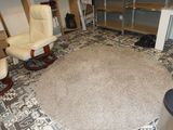 une photo d'un salon avec un tapis et des fauteuils