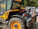 a yellow and black tractor parked in a gravel lot