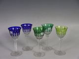 six different colored wine glasses are lined up on a white surface