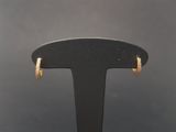a pair of gold hoop earrings on a black stand