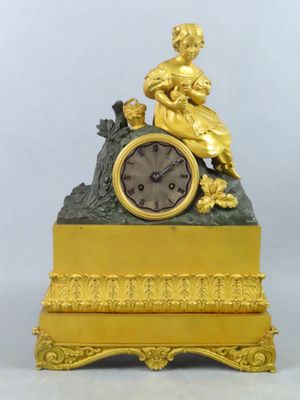 une horloge en or avec une femme assise dessus