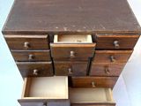 a small wooden chest of drawers on a white surface