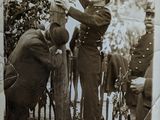 an old photo of a man helping another man up on a pole