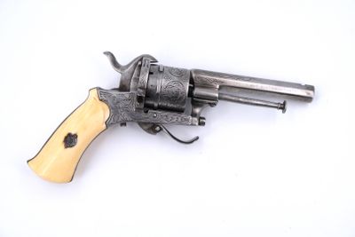 un petit revolver avec une crosse en bois posé sur une surface blanche