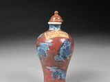 a red vase with blue flowers on it on a white surface