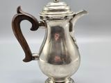 a silver coffee pot with a wooden handle on a white surface