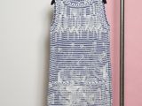 a blue and white dress hanging on a rack in front of a pink wall