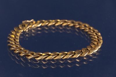 un gros plan d'un bracelet en or sur un fond bleu
