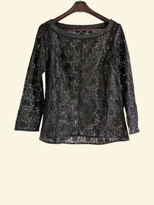 a black top with sequins on it hanging on a hanger