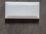 a close up of a white rectangular tile on a gray surface