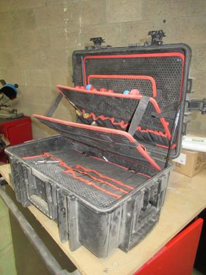 une valise noire avec des poignées rouges posée sur une table