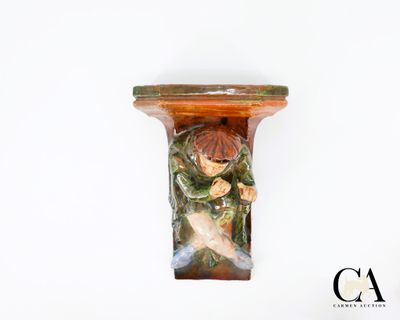 une figurine représentant un garçon tenant un poisson, posée sur une étagère