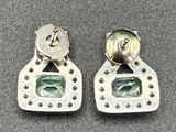 pair of silver and green stone earrings on a gray surface