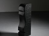 une sculpture noire représentant une tête d'homme, à côté d'une chaise noire