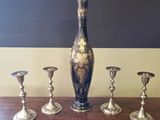 five silver candlesticks and a vase on a table