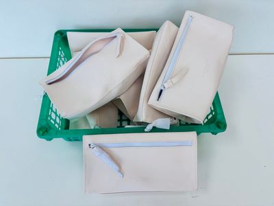 un panier vert rempli de sacs à main blancs posé sur une table blanche
