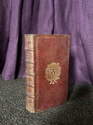 un vieux livre posé sur une table, à côté d'un rideau violet
