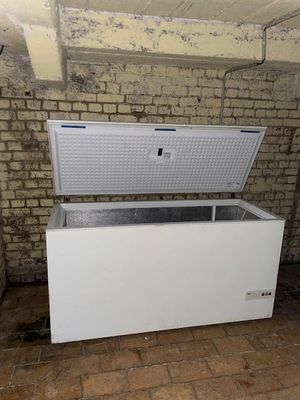a white chest freezer sitting in front of a brick wall