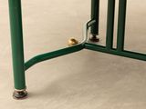 a green table with a glass top and metal legs