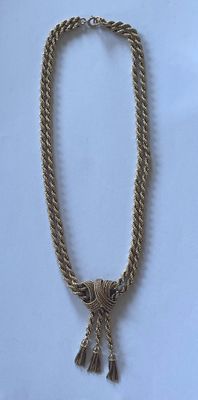 collier doré orné de pompons sur fond blanc