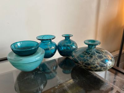 three blue glass vases sitting on a glass table