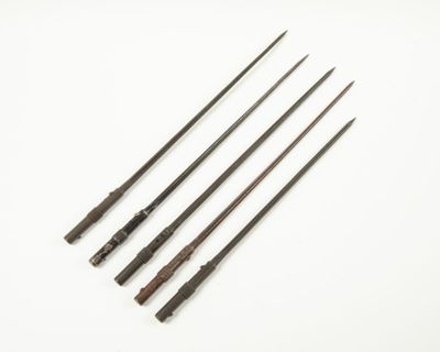 un ensemble de quatre outils métalliques à l'ancienne posés sur une surface blanche