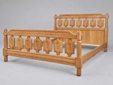 un lit dont le cadre en bois présente des sculptures sur la tête de lit