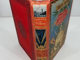 an old book with a red cover sitting on top of a white table